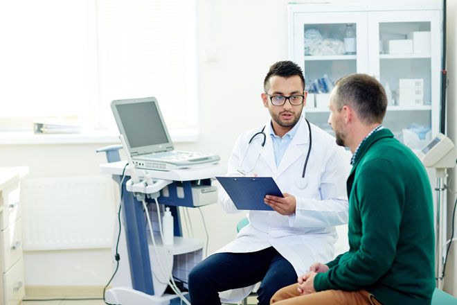 A doctor is talking to a patient next to a computer
